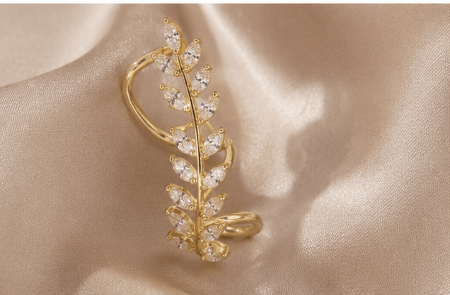 Gold leaf ear cuff with clear crystals, elegant women's fashion jewelry on satin background
