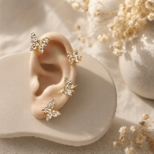 Gold butterfly stud earrings with crystal details, displayed on ear model with dried flowers